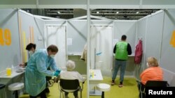 Щеплення від COVID-19 у центрі вакцинації обладнаному у будівлі торговельних виставок у Берліні в Німеччині 18 січня 2021 р.