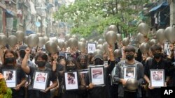 Pengunjuk rasa anti-kudeta memegang foto orang-orang yang tewas dalam protes terhadap militer menawarkan doa untuk mereka, di Yangon, Myanmar, Senin, 5 April 2021. (Foto: AP)