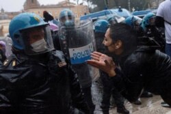 A demonstrator gestures as she speaks to a police officer during a protest of restaurant and small-business owners who call for their businesses to be allowed to reopen amid the coronavirus outbreak, in Rome, Italy, April 12, 2021.