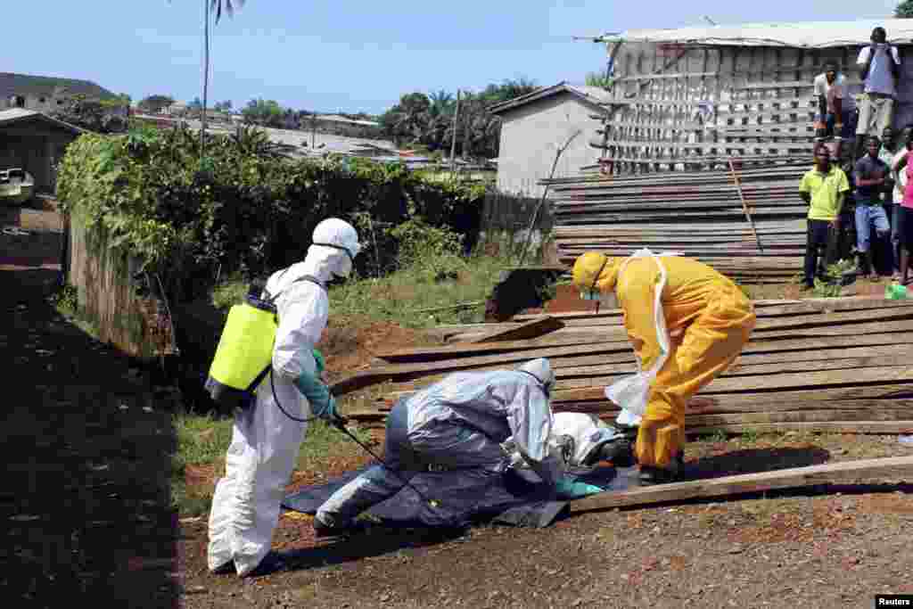 Sog&#39;liqni saqlash xodimlari Liberiyada Eboladan o&#39;lgan ayolning jasadini olib ketmoqda, 14-oktabr, 2014-yil. 