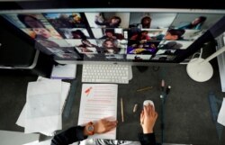 FILE - A student takes classes online with his companions using the Zoom app at home.