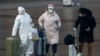 A passenger wearing a full-body protective suit catches the eyes of others as they walk out from the Beijing railway station in Beijing, Feb. 11, 2020. 