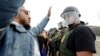 A man faces Border Patrol agents during a protest, Dec. 10, 2018, in San Diego. The protest organized by a Quaker group called for an end to detaining and deporting immigrants and showed support for a caravan of Central American asylum seekers. 