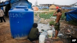 FILE PHOTO - A Cambodian bathes near his slum home Thursday, Feb. 19, 2009, on the outskirts of Phnom Penh, Cambodia. (AP Photo/David Longstreath)