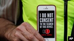 Seorang pria mengangkat iPhone miliknya untuk mendukung demo privasi di luar toko Apple di San Fransicso, Calif., 23 Feb 2016.