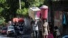 FILE - People carry their belongings along a street as they flee their homes from gang violence, in Port-au-Prince, Haiti, Oct. 26, 2024.
