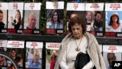 Seorang perempuan di Tel Aviv, Israel berhenti sejenak dekat poster-poster warga Israel yang masih disandera Hamas di Jalur Gaza ketika Kabinet keamanan Israel sedang rapat untuk membahas gencatan senjata dengan Hamas, Jumat, 17 Januari 2025. (Foto: Maya Alleruzzo/AP Photo)