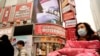 Residents wearing masks past by a screen showing a trailer for the film "Days and Nights in Wuhan" outside a mall in Wuhan in central China's Hubei province on Jan. 22, 2021.