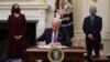 U.S. President Joe Biden signs executive orders as part of the COVID-19 response as U.S. Vice President Kamala Harris, left, and Director of NIAID Anthony Fauci look on in the State Dining Room of the White House in Washington, Jan. 21, 2021. 