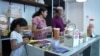 Sri Themudu, right, packages gift baskets for customers along with his wife, Praveena Sarva, and 7-year-old daughter, Diyaa. It’s a seasonal business for Deepavali, the Indian festival of lights. (Dave Grunebaum/VOA)