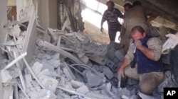 FILE - This image posted on the Twitter account of Syria Civil Defence, also known as the White Helmets, a volunteer search and rescue group, shows the aftermath of an airstrike in Talbiseh, Syria, Sept. 30, 2015.