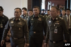 Letjen Manas Kongpan (tengah) diapit polisi saat menyerahkan diri di mabes kepolisian di Bangkok (3/6)