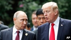 U.S. President Donald Trump and Russia's President Vladimir Putin talk during a photo session at the APEC Summit in Danang, Vietnam, Nov. 11, 2017. 