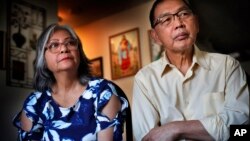 In this Dec. 1, 2017 photo, Poppy Sombah, left, and Freddy Sombah listen to an Indonesian community leader at their home in Somersworth, New Hampshire. The couple fled Indonesia to escape harassment from their Muslim neighbors following Poppy's conversion.