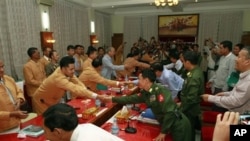 Members of Myanmar government negotiators, right, shake hands with representatives of the Shan State Army (SSA).