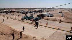 FILE - Iraqi security forces and vehicles are seen at the border crossing between the Iraqi town of Qaim and Syria's Boukamal, in Qaim, Iraq, Sept. 30, 2019. Drones reportedly attacked a convoy in the region Sunday.