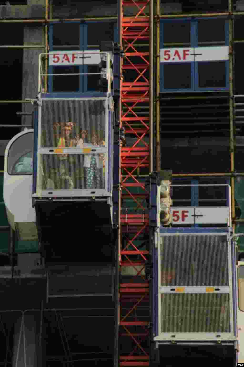 Workers look down from an elevator at the construction site of Olympia City, September 29, 2014. (Nov Povleakhena/VOA Khmer) 