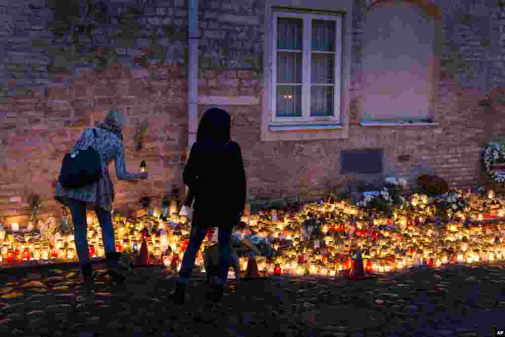Warga menyalakan lilin di luar Kedutaan Besar Perancis di Vilnius, Lithuania (15/11), untuk para korban serangan maut di Paris. ​(AP/Mindaugas Kulbis)