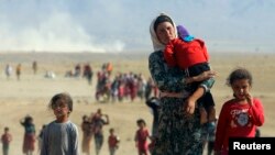 Displaced people from the minority Yazidi sect, fleeing violence from forces loyal to the Islamic State in Sinjar town, walk towards the Syrian border, on the outskirts of Sinjar mountain, near the Syrian border town of Elierbeh of Al-Hasakah Governorate 