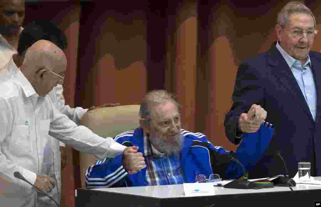 Fidel Castro duduk sambil menggenggam tangan adiknya, Presiden Kuba Raul Castro (kanan) dan Wakil II Komite Pusat, Jose Ramon Machado Ventura, sebelum dimainkannya himne Partai Komunis dalam upacara penutupan Kongres Partai Komunis Kuba ke-7, di Havana, 19 April 2016. (Ismael Francisco/Cubadebate via AP)