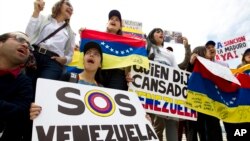 Manifestan ki t ap pwoteste kont rejim Nicolàs Maduro a.... Enskripsyon ki sou youn nan pannkat yo (a goch) vle di "Sekou pou Venezuela"..