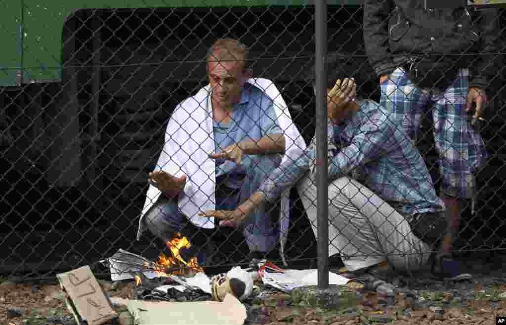 Men burn papers to warm themselves outside a train that was stopped in Bicske, Hungary, Sept. 4, 2015. 
