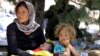 A displaced family from the minority Yazidi sect, fleeing the violence in the Iraqi town of Sinjar, waits for food while resting at the Iraqi-Syrian border crossing in Fishkhabour, Dohuk province August 13, 2014.