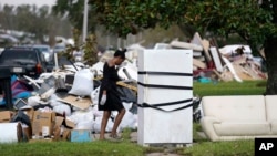 Seorang warga bernama Lori Butler tampak menyeka keningnya saat ia berusaha memindahkan puing puing dari rumahnya yang terendam banjir akibat diterjang badai Ida di LaPlace, Louisiana, AS, pada 7 September 2021. (Foto: AP)