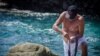 On the Pacific Coast of Oaxaca, Mexico, a shirtless Mixtec man presses a snail’s foot to encourage it to secrete a neurotoxin directly onto a skein of cotton yarn, which results in a brilliant reddish purple hue. (True Colors by Keith Recker)