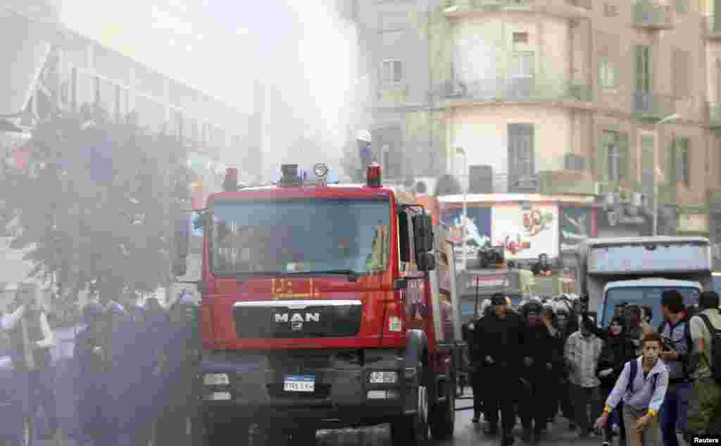 Riot police fire a water cannon to disperse people protesting a new law restricting demonstrations, in downtown Cairo, Nov. 26, 2013.