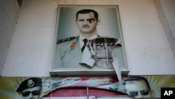 FILE - Serangkaian poster memperlihatkan foto mendiang Presiden Suriah Hafez Assad dan putranya, mantan presiden Suriah Bashar Assad, di pintu masuk pusat penahanan keamanan terkenal yang disebut Cabang Palestina, di Damaskus, Suriah, Sabtu, 14 Desember 2024. (Hussein Malla/AP)