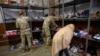 Seorang pengungsi asal Afghanistan tampak mencari sepatu yang merupakan hasil donasi pada pusat donasi di pangkalan militer Fort McCoy, Wisconsin, AS, pada 30 September 2021. (Foto: AP/Barbara Davidson)