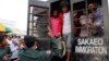 Cambodian migrant workers get off from a Thai truck upon their arrival from Thailand at Cambodia-Thai international border gate in Poipet, Cambodia, Tuesday, June 17, 2014.