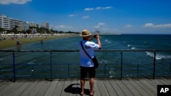 FILE - A tourist takes photos the view from the sea in southeast coast city of Larnaca in the eastern Mediterranean island of Cyprus, June 1, 2021. 