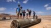 Ljudi stoje na ostacima iranskog projektila u pustinji Negev blizu Arada, 2. oktobra 2024. godine, nakon iranskog raketnog napada na Izrael. (Foto: Menahem Kahana/AFP)