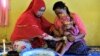 Seorang balita perempuan duduk di pangkuan ibunya dalam upacara sunat di Gorontalo, Provinsi Gorontalo, 20 Februari 2017. (Foto: Bay Ismoyo/AFP)