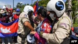 Local security personnel guards confiscate a loudspeaker from a protester during a protest to mark the 29th anniversary of the Paris Peace Accord in front of the US embassy in Phnom Penh on October 23, 2020. (Photo by TANG CHHIN Sothy/AFP)