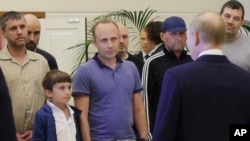 FILE - Pablo Gonzalez, a freelance journalist from Spain who had been based in Poland since 2019, second from left with shaved head, listens to Russian President Vladimir Putin, back to camera, speaking to "swapped" Russian prisoners upon their arrival in Moscow on Aug. 1, 2024.