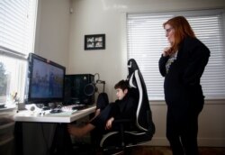 Tracey Pucci dan putranya, Foxton Harding, 12, menonton video latihan yang dibuat oleh para guru Foxton di Northshore Middle School ketika sekolah beralih ke pembelajaran online selama dua minggu di rumah mereka di Bothell, Washington, AS, 11 Maret 2020.