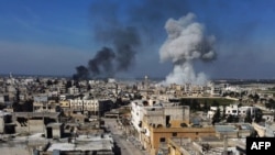 Asap mengebul di kota Saraqeb, di bagian timur provinsi Idlib di Suriah barat laut, menyusul pemboman oleh pasukan pemerintah Suriah, 27 Februari 2020.