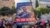 Para pemrotes Israel, mengenakan masker di tengah pandemi Covid-19 sambil memegang poster PM Benjamin Netanyahu di luar kediaman resminya di Yerusalem, 24 Juli 2020.