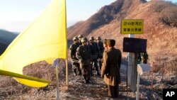 Tentara Korea Selatan, mengenakan helm, bersiap melintasi Garis Demarkasi Militer sementara tentara Korea Utara berdiri di dalam Zona Demiliterisasi (DMZ) di Cheorwon, 12 Desember 2018. (Foto: via AP)