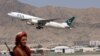 Seorang pejuang Taliban tampak berjaga sementara pesawat dari maskapai Pakistan International Airlines, lepas landas meninggalkan Bandara Internasional Kabul pada 13 September 2021. (Foto: AFP/Karim Sahib)
