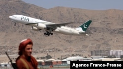 Seorang pejuang Taliban tampak berjaga sementara pesawat dari maskapai Pakistan International Airlines, lepas landas meninggalkan Bandara Internasional Kabul pada 13 September 2021. (Foto: AFP/Karim Sahib)