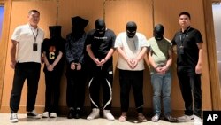 FILE - In this photo released by Xinhua News Agency, Myanmar police hand over five telecom and internet fraud suspects to Chinese police at Yangon International Airport in Yangon, Myanmar, Aug. 26, 2023. 