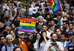 A man walks through the crowd holding a sign during a vigil and memorial for victims of the Orlando nightclub shootings near the historic Stonewall Inn in New York, June 13, 2016.