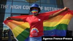 FILE - An activists carries a rainbow flag outside the Botswana High Court as the country's appeals court starts hearing a government attempt to overturn a landmark ruling that decriminalized homosexuality, Oct. 12, 2021.
