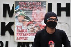 Seorang pengunjuk rasa duduk di sebelah spanduk bertuliskan "Aktivis penculikan 1997-1998, TNI harus bertanggung jawab, 20 Mei 2014. (Foto: AFP)