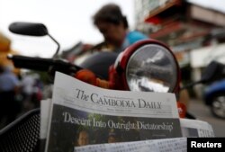 FILE - A woman buys the final issue of The Cambodia Daily newspaper at a store along a street in Phnom Penh, Cambodia, September 4, 2017. (REUTERS/Samrang Pring)
