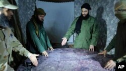 FILE - This undated photo released by a militant group in 2016, shows Abu Mohammed al-Golani of the militant Levant Liberation Committee and the leader of Syria's al-Qaida affiliate, second right, discussing battlefield details with field commanders over map, in Aleppo, Syria.